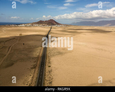 Aerial view of a desert landscape on the island of Lanzarote, Canary Islands, Spain. Road that crosses a desert. Tongue of black asphalt in the desert Stock Photo