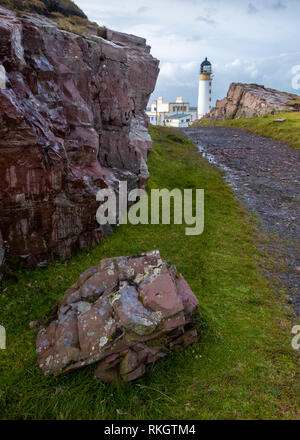 Rocks and and a gravel path leading towards Rua Reidh lighthouse on a sunny and cloudy day at the entrance to Loch Ewe, Wester Ross, Scotland Stock Photo