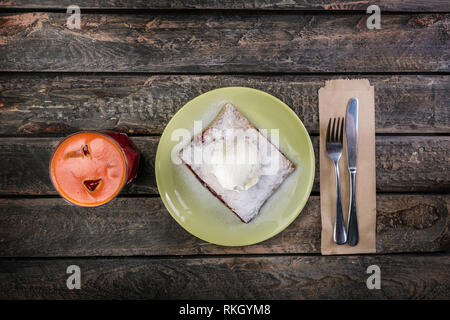 Strudel with cherry and vanilla ice cream, served on the ceramic plate with the cutlery and the glass of beverage. Stock Photo