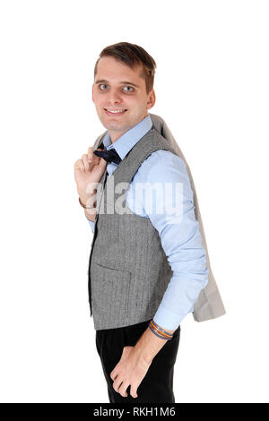 A handsome young man standing in a gray vest and dark pants with his gray jacket over his shoulder, isolated for white background Stock Photo