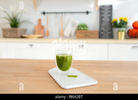 Matcha green tea in glass cup with kitchen on the background Stock Photo