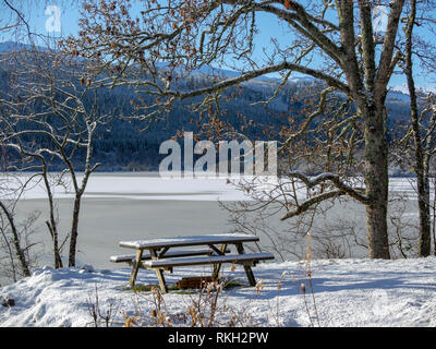 Snow covered picnic table by frozen Loch Meiklie, Glen Urquhart, Highland, Scotland Stock Photo