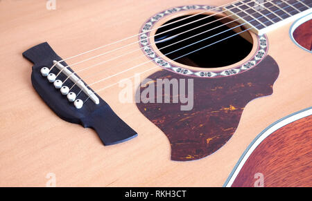 Classic acoustic six strings guitar natural color top from spruce with cutaway fragment on jeans background vertical view closeup Stock Photo