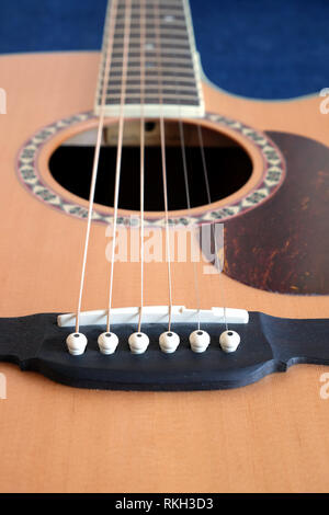 Classic acoustic six strings guitar natural color top from spruce with cutaway fragment with long neck on jeans background vertical view closeup Stock Photo