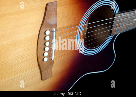 Classic acoustic six strings guitar sunburst color top from spruce with cutaway fragment isolated on black background side view closeup Stock Photo