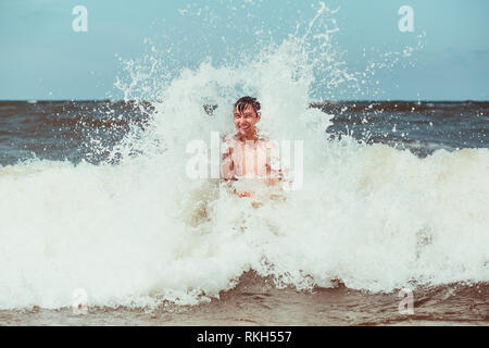 Young man enjoying the high waves in the sea during a summer vacations. Spending a summer holiday by the sea Stock Photo