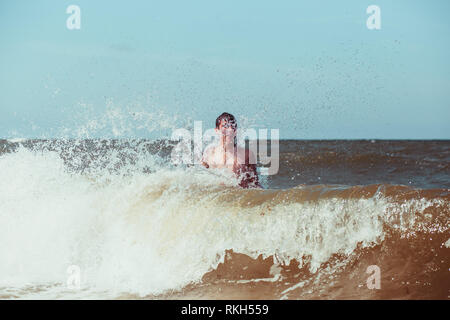 Young man enjoying the high waves in the sea during a summer vacations. Spending a summer holiday by the sea Stock Photo