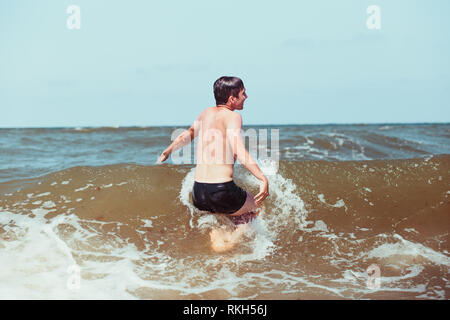 Young man enjoying the high waves in the sea during a summer vacations. Spending a summer holiday by the sea Stock Photo