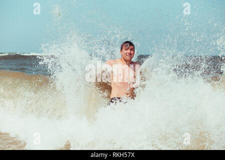 Young man enjoying the high waves in the sea during a summer vacations. Spending a summer holiday by the sea Stock Photo