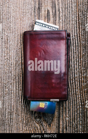Leather wallet with dollar banknotes, credit card on wooden desk. Portrait orientation Stock Photo