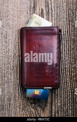 Leather wallet with euro banknotes, credit card on wooden desk. Portrait orientation Stock Photo