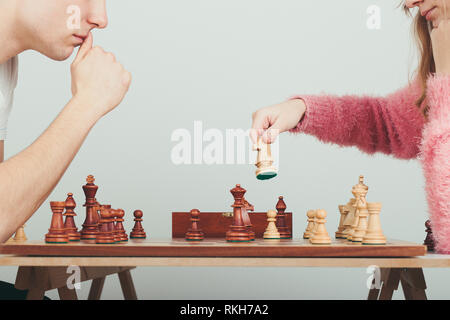 Girl and boy playing chess at home. Girl moving her piece. Teenagers sitting by a table. Profile view. Copy space for text at the top and bottom of im Stock Photo