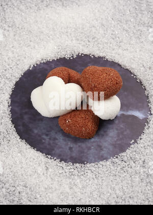 White and brown heart shaped sugar cubes, on blue background Stock Photo