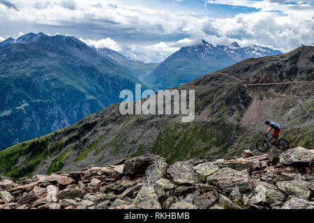 A man rides a mountain bike on a rocky trail in the Austrian resort of Sölden in the Ötztal Valley during the summer months. Stock Photo
