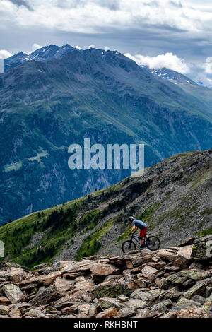 A man rides a mountain bike on a rocky trail in the Austrian resort of Sölden in the Ötztal Valley during the summer months. Stock Photo