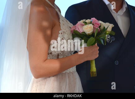 Young bride in a white lace halter top wedding dress walking down the aisle at a tropical resort hotel. Destination wedding in a tropical garden. Stock Photo