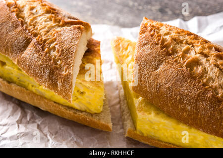 Bocadillo de tortilla española. Spanish potato omelette sandwich on wooden table. Stock Photo