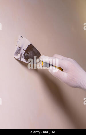 the repair of the walls, a man in a blue glove with a spatula Stock Photo