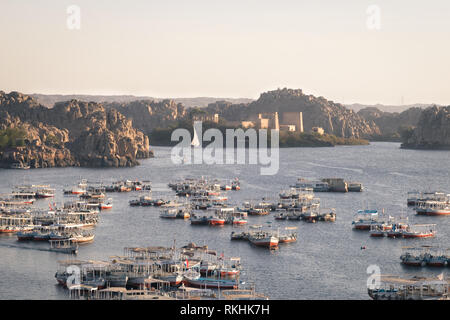 ISIS Temple at the Aswan Old Dam lake (Egypt) with traditional boats at sunset time Stock Photo