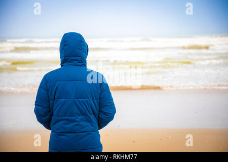 Young man in jacket on sandy beach of Rimini in winter, Italy Stock Photo
