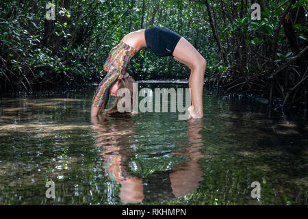 Young woman practicing yoga (Wheel Pose - Urdhva Dhanurasana) in a natural setting - Fort Lauderdale, Florida, USA Stock Photo