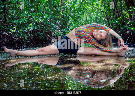 Young woman practicing yoga (Straddle Split) in a natural setting - Fort Lauderdale, Florida, USA Stock Photo