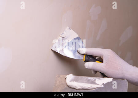Hand with putty knife repair wall, Hand with a spatula, spatula with spackle paste structure, process of applying layer of putty trowel, working with  Stock Photo