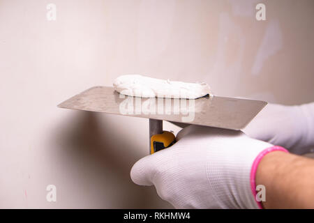 Hand with putty knife repair wall, Hand with a spatula, spatula with spackle paste structure, process of applying layer of putty trowel, working with  Stock Photo