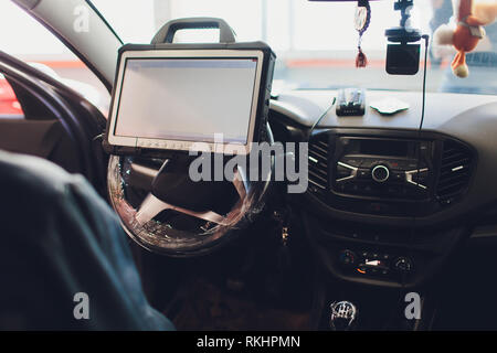 car mechanic maintains a vehicle with the help of a diagnostic computer - modern technology in the car repair shop Stock Photo