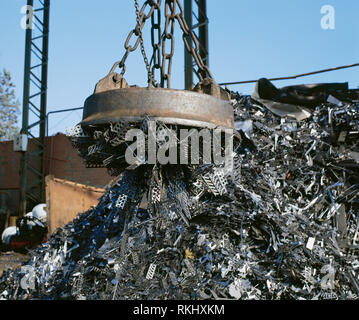 Electromagnet on crane lifting metal at scrap yard. Stock Photo