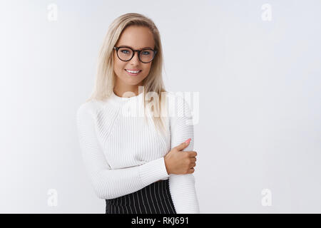 Shy new female office assistant talking to coworker feeling awkward and timid, touching arm unconfident and flirty smiling friendly at camera posing Stock Photo