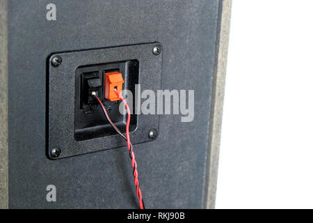 Red and black twisted wire connected to cable connection socket on rear side speaker system box side view isolated closeup Stock Photo