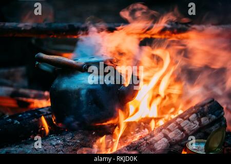 https://l450v.alamy.com/450v/rkjd0k/black-old-retro-iron-camp-kettle-boiling-water-on-a-fire-in-forest-bright-flame-fire-of-bonfire-at-dusk-night-rkjd0k.jpg