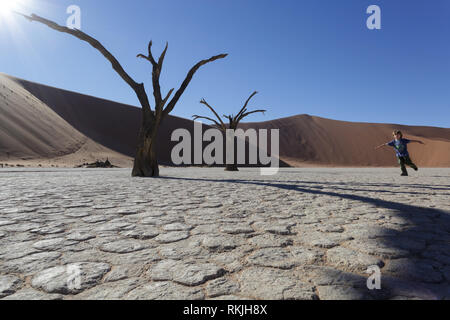 Playful caucasian 5 year old boy running among ancient camelthorn trees on pan, Deadvlei, Namibia, Africa Stock Photo