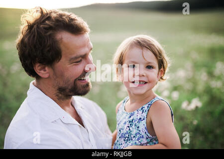 Young father in nature holding small daughter in the arms. Stock Photo