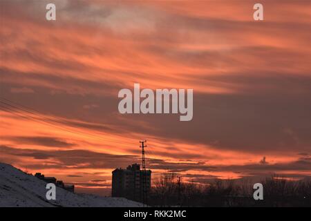 Ankara, Turkey. 10th Jan, 2019. Clouds cover a blood red sky over trees and a residential building during sunset in a western suburb. Credit: Altan Gocher | usage worldwide/dpa/Alamy Live News Stock Photo