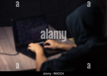 Dangerous hooded hacker on laptop breaks internet code and spread virus on a computer systems Stock Photo