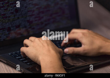 Dangerous hooded hacker on laptop breaks internet code and spread virus on a computer systems Stock Photo