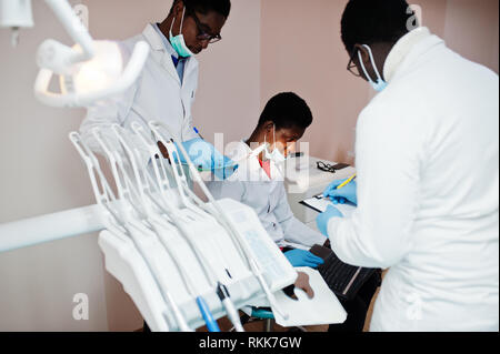 Three african american male doctors working with laptop, discussing with colleagues in dental clinic. Stock Photo