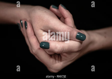 Women hands holding together closeup shot of hands with green painted nails Stock Photo