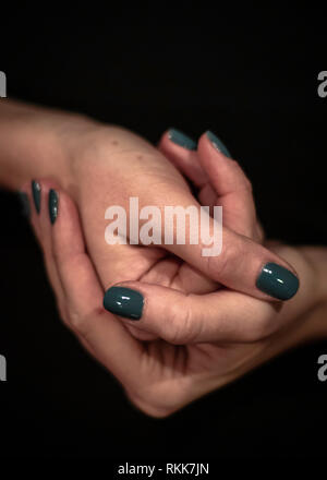 Women hands holding together closeup shot of hands with green painted nails Stock Photo