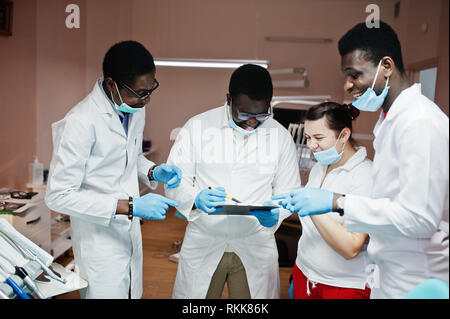 Multiracial dentist doctors team. Three african american male doctors with one caucasian doctor female. They discussing and laughing. Stock Photo