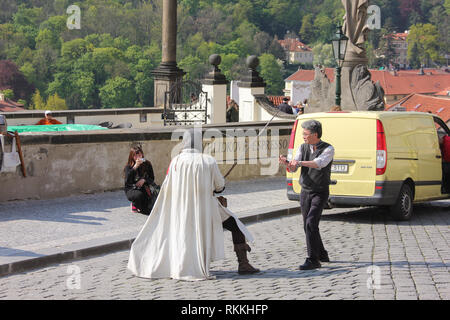 Prague, Czech Repulic - May, 2016: Asian tourists taking photo near Prague Castle playing battle with costume medieval knight reenactment scene Stock Photo