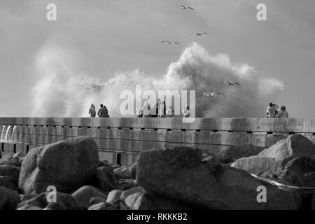 Porto, Portugal - December 31, 2015: Tourists seeing the big stormy sea waves in the Douro river mouth Stock Photo