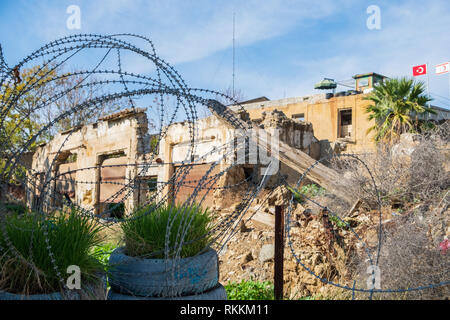 Barbed wire and a sentry post with flags in the background at the United Nations buffer zone (Green line) in divided Nicosia, capital of the island of Stock Photo