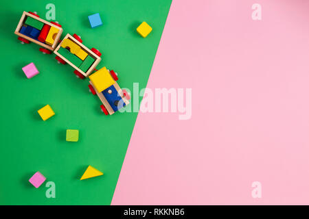 Toy background. Wooden toy train with colorful cubes on pink and green background Stock Photo