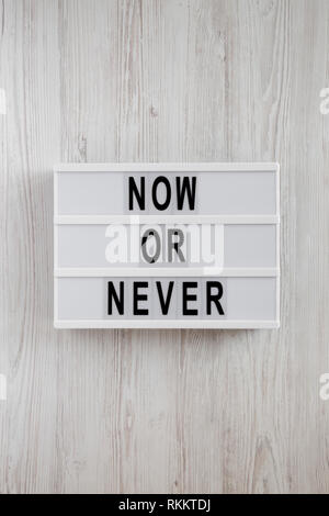 'Now or never' word on modern board on a white wooden table, top view. From above, flat lay, overhead. Stock Photo