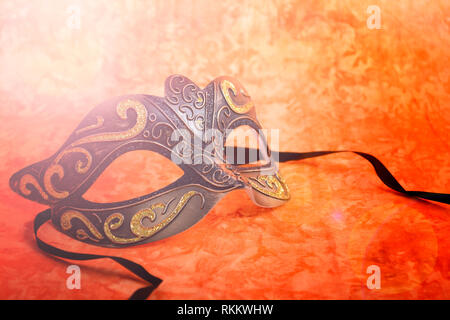 Mardi Gras mask on a bright, colorful orange background, closeup with lens flare. Stock Photo