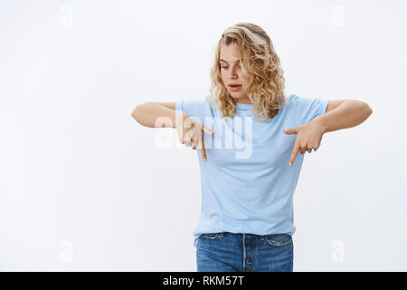 Woman cannot hide excitement and interest as looking and pointing down at cool product gazing intrigued and curious examining awesome advertisement Stock Photo