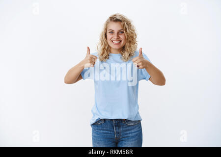 Good job. Portrait of optistic and supportive charming cute blond girlfriend with blue eyes smiling nice and cute as cheer up friend showing thumbs up Stock Photo